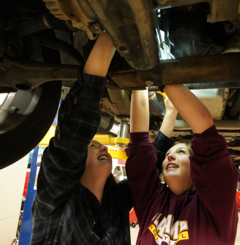 two student working on a car in automotive class